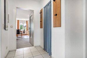 A hallway with a dining area, a door, and a curtain. - Apartment 'Ringstr. 21, 2. OG Links WE55' with Balcony and Wi-Fi (Binz)