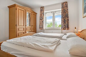 A bedroom with two beds, a wardrobe, a window with curtains, and a nightstand with a lamp. - Apartment 'Ringstr. 21, 2. OG Links WE55' with Balcony and Wi-Fi (Binz)