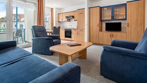 A modern living room with a sofa, a coffee table, and a TV. - Apartment 'Ringstr. 21, 2. OG Links WE55' with Balcony and Wi-Fi (Binz)