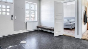 Una habitación con una banca, una cama, un radiador y una puerta que da a otra estancia.