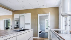 Una cocina moderna con armarios blancos, suelo de madera y vistas al exterior.
