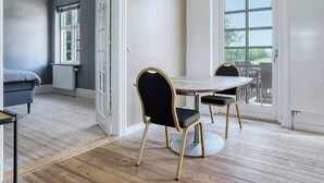 Un comedor con una mesa y sillas, vistas a través de un ventanal y una puerta que conduce a otra habitación.