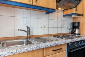 Cozinha com pia de aço inoxidável, forno duplo e cafeteira.