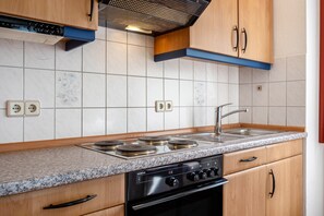 Eine Küche mit Gasherd, Backofen, Spülbecken und Holzschränken.