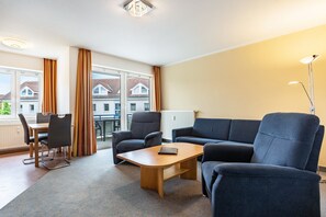 Ein modernes Wohnzimmer mit Sofa, Sesseln, Couchtisch und Essbereich.