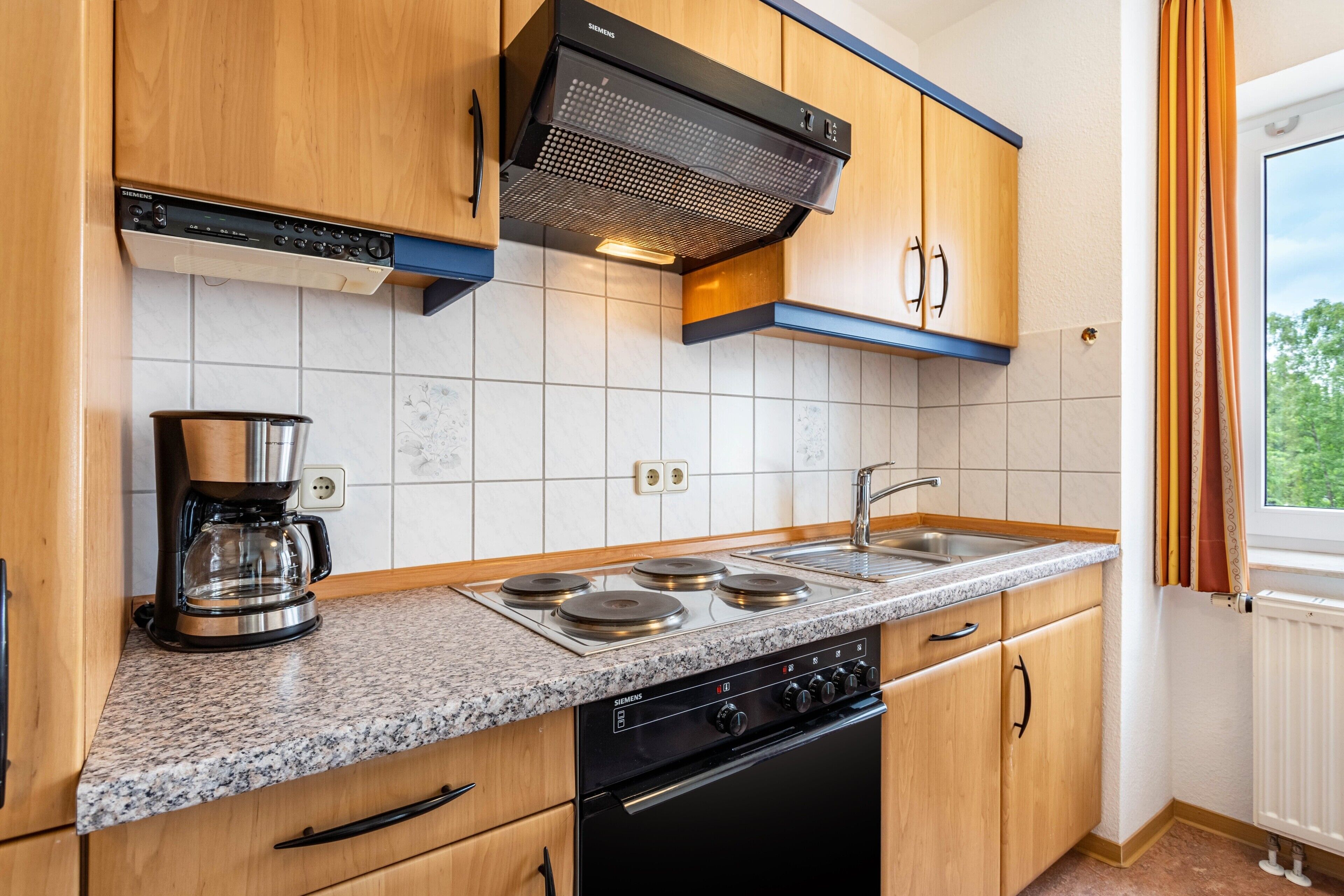 A modern kitchen with a built-in stove, coffee maker, and stainless steel sink.