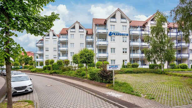 A multi-story hotel with balconies, a paved driveway, and surrounding greenery. - Apartment 'Ringstr. 22, 1. OG Rechts WE44' with Balcony and Wi-Fi (Binz)