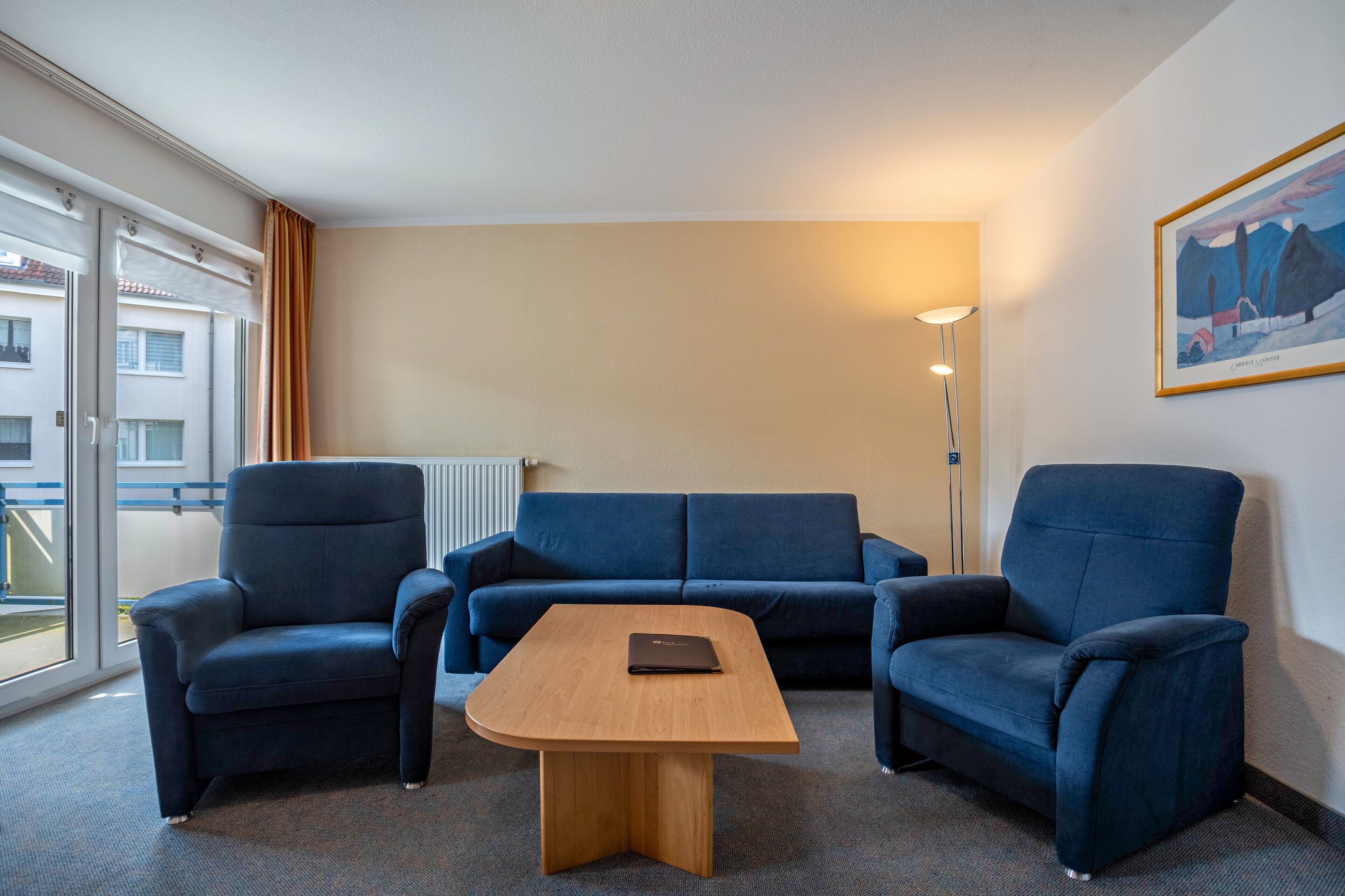 Hotellihuone, jossa on sohvaryhmä, puinen sohvapöytä ja taulu seinällä.