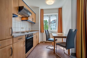 Eine kleine Küche mit Holzschränken, einem Herd und einem Fenster mit Vorhängen.