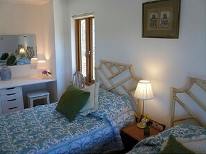 Quarto com cama, mesa de cabeceira, luminária, cadeira e janela com vista.
