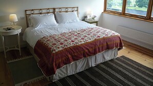 A bedroom with a bed, two bedside tables, a window with a view, and three framed pictures on the wall. - Willow Cottage (Presteigne)