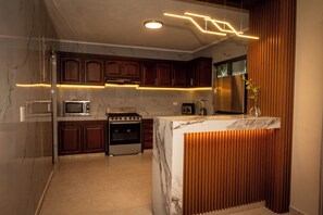 A modern kitchen with marble countertops, wooden cabinets, and a built-in stove. - Casa Mía : Private pool : 3 Bedrooms (cancun)
