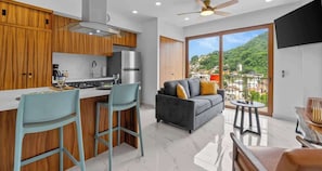 A modern kitchen with wooden cabinets, a stainless steel refrigerator, and a bar area with two stools. - Rooftop Pool & Ocean Views in Zona Romántica (Puerto Vallarta)