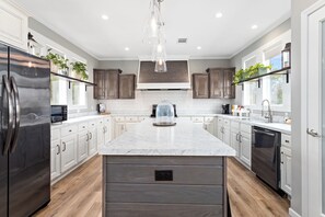 Una cocina moderna con una isla grande, electrodomésticos de acero inoxidable y armarios de madera.