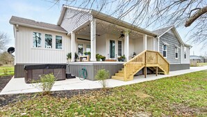 Een huis met twee verdiepingen, voorzien van een overdekte veranda, een houten trap en een schotelantenne.