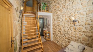 Un escalier menant à un deuxième étage, une salle de bain avec douche et un mur en pierre.