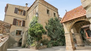 Un bâtiment en pierre avec un toit en tuiles, une arche et une petite fenêtre.