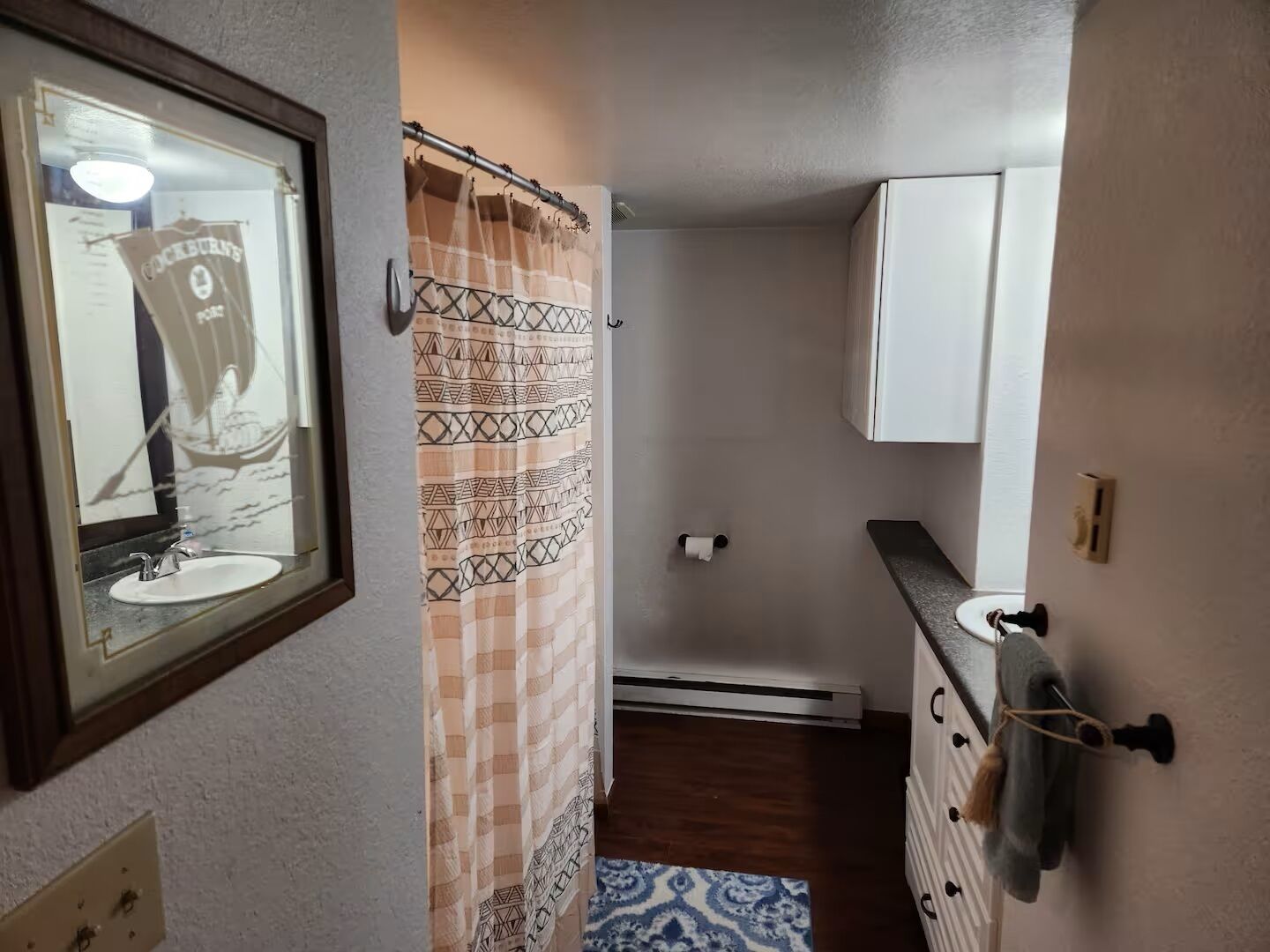 A bathroom with a shower curtain, a sink, a towel rack, and a mirror.