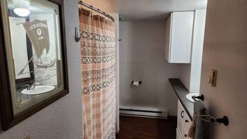 A bathroom with a shower curtain, a sink, a towel rack, and a mirror.