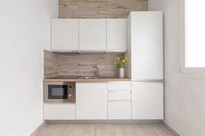 A modern kitchen with white cabinetry, a built-in microwave, and a stainless steel sink. - Borgo Climmena - Bilo con veranda (Manduria)