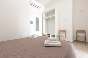A bedroom with a bed, a closet, two chairs, and a towel stack. - Borgo Climmena - Bilo con veranda (Manduria)