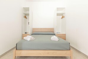 A bed with a wooden frame, a green bedspread, and two towels on the side. - Borgo Climmena - Bilo con Patio (Manduria)