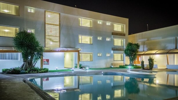 Un hôtel moderne doté d’une piscine, de nombreux balcons et de grandes fenêtres bien éclairées.