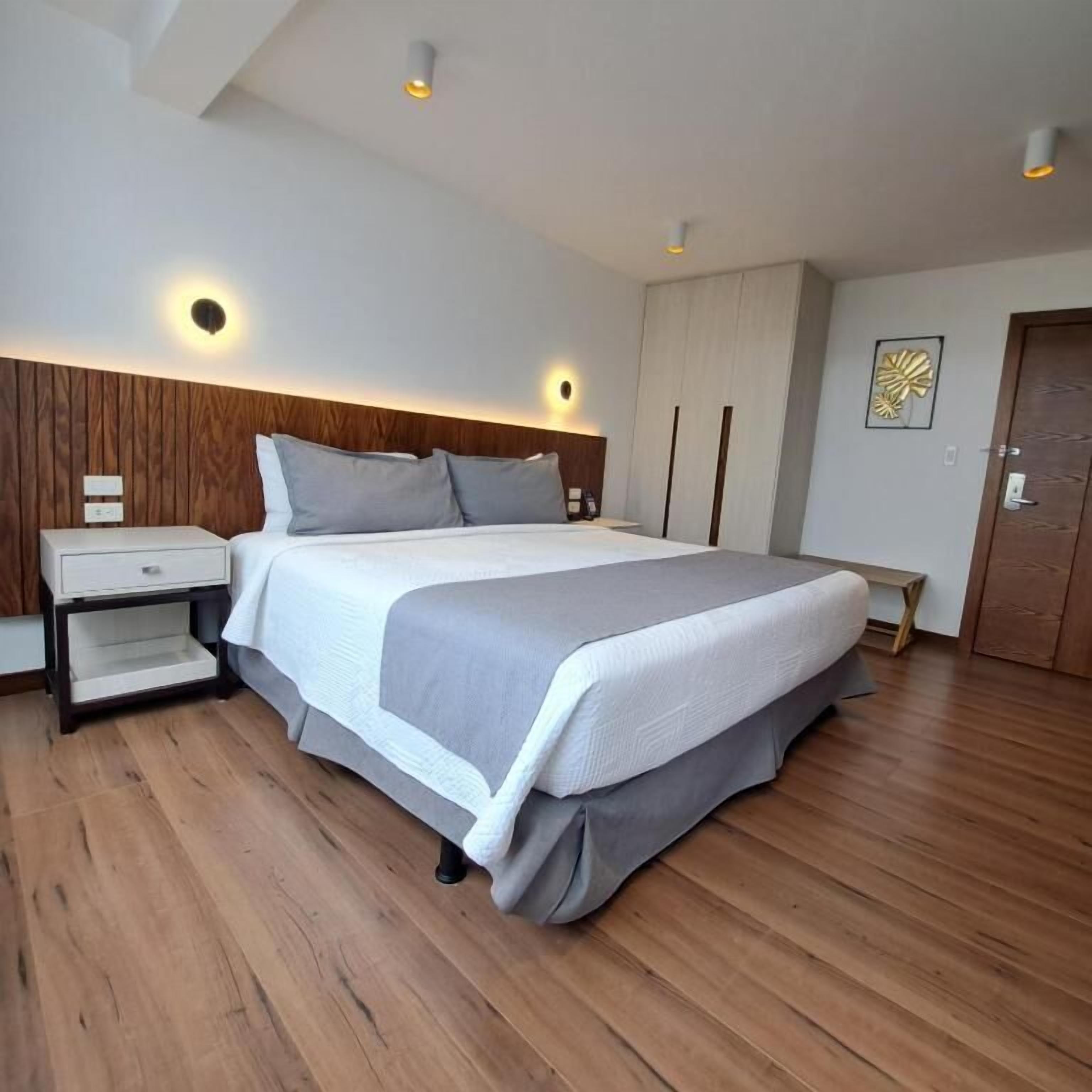 A modern bedroom with a large bed, wooden headboard, bedside tables, and a wardrobe.