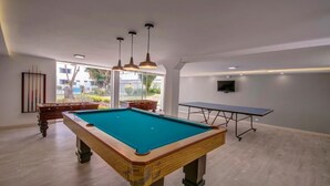 Une table de billard, une table de ping-pong, un téléviseur et une vue sur l’extérieur.