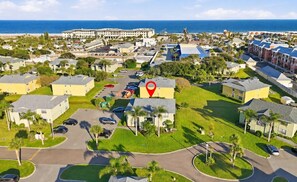 Vista aérea de una zona residencial con varios edificios, caminos y una gran masa de agua al fondo.