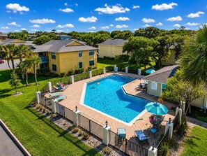 Zona residencial con piscina, sillas de descanso y patio amurallado.