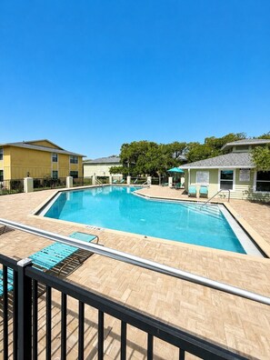 A swimming pool with a tiled deck, a fence, and a small pavilion with a sign. - Anastasia Hideaway 6 Min Walk to Beach Community Pool Near Dining & Amphitheatre (St. Augustine)