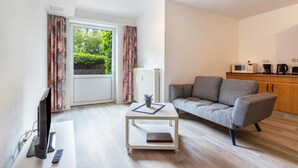 Una sala moderna con televisor de pantalla plana, un sofá, una mesa de centro y una zona de cocina con electrodomésticos.