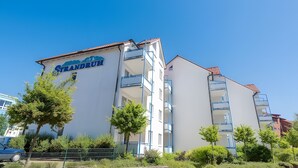 Un edificio de varios pisos con balcones, un letrero que dice 'Grandruth' y un cielo azul despejado.