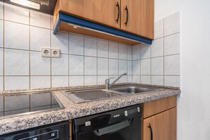 Een keuken met een dubbele spoelbak, een vaatwasser en houten kastjes.