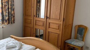 A bedroom with a bed, a wooden wardrobe, a chair, and a radiator. - Apartment 'Mais. Ringstr. 22, 3.OG Rechts WE48' with Balcony and Wi-Fi (Binz)