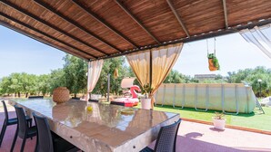 An outdoor patio with a glass-top table, chairs, a flamingo float, and potted plants. - Villa Latina Apartment in villa with garden, Wi-Fi and air conditioning (Solarino)