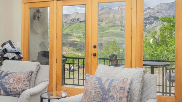 Una habitación con sofá, una mesita y vistas a un paisaje montañoso a través de amplios ventanales.