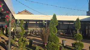 A patio area with potted plants, string lights, and outdoor seating. - Hotel Sunrise (Delchevo)