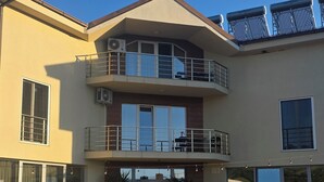 A two-story building with a balcony, large windows, and outdoor seating area. - Hotel Sunrise (Delchevo)