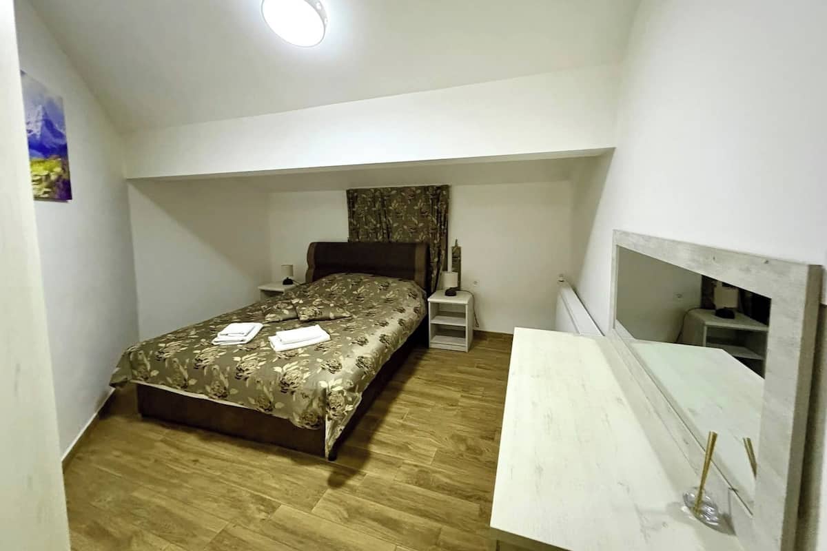 Un dormitorio con cama, mesitas de noche, un espejo y una lámpara en el techo.