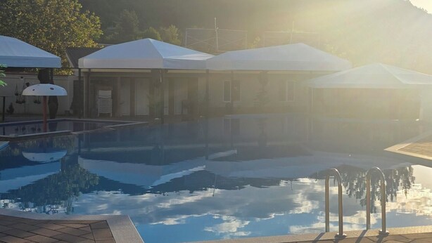 A swimming pool with a clear sky and mountains in the background. - Hotel Sunrise (Delchevo)