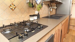 Cozinha com fogão a gás, pia e painel de azulejos.