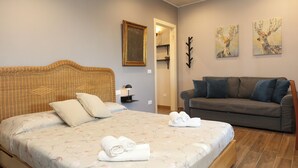 Quarto com cama, sofá e duas pinturas penduradas na parede.