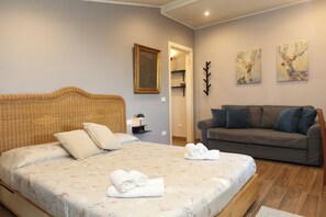 Un dormitorio con una cama, un sofá y dos cuadros colgados en la pared.