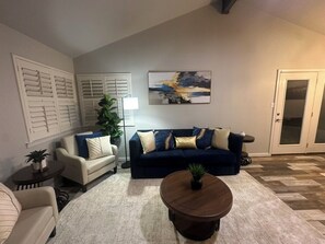 A living room with a sofa, two chairs, a coffee table, a lamp, and a painting on the wall. - Vine Cottage- A Spacious, charming home-Walk to the square and SWU! (Georgetown)