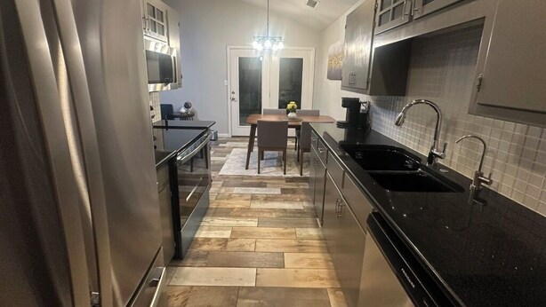 A kitchen with a stainless steel refrigerator, a black countertop sink, and a dining area with a table and chairs. - Vine Cottage- A Spacious, charming home-Walk to the square and SWU! (Georgetown)
