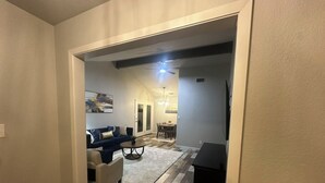 A hallway leading to a living room with a sofa, a coffee table, and a TV stand. - Vine Cottage- A Spacious, charming home-Walk to the square and SWU! (Georgetown)