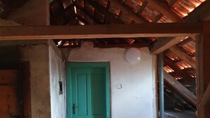 Un edificio rustico con una porta verde, un muro bianco e un soffitto in legno.