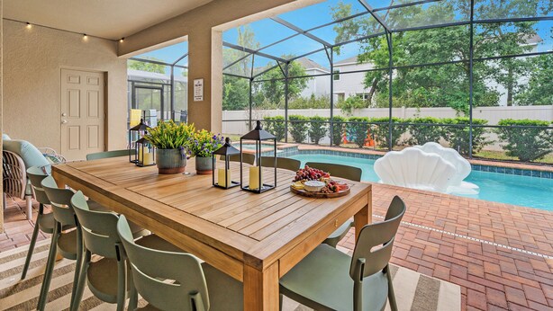 A wooden dining table with chairs, a potted plant, candles, and a fruit platter. - NEW! Princess Theme! Minutes to Disney World! Private Pool and Hot tub! Theatre! (Kissimmee)